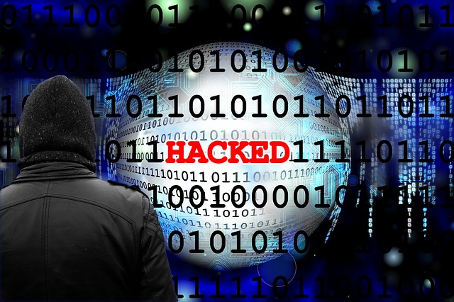 Man in hoodie facing of grid of numbers, zero's and one's, with red text reading 'HACKED' in the center.