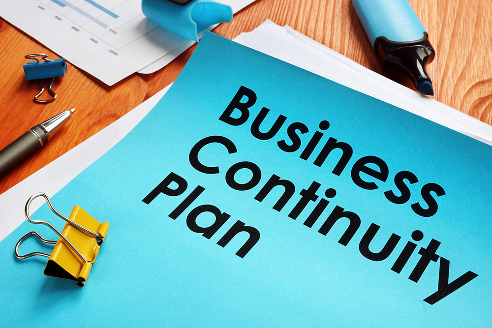 A document on a work desk with the words business continuity plan on the cover